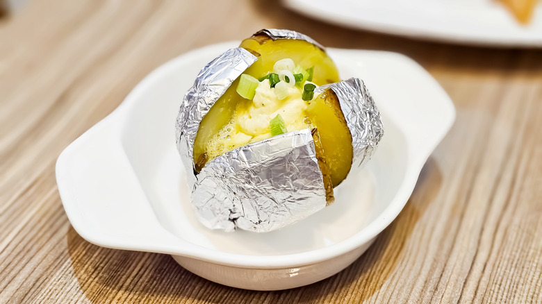 Foil-wrapped baked potato in a dish