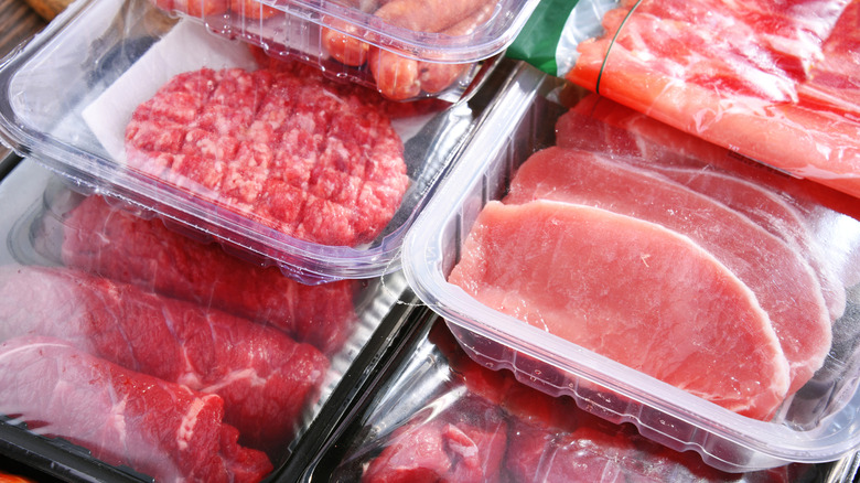 Assorted plastic-wrapped meats in a stack at a grocery store