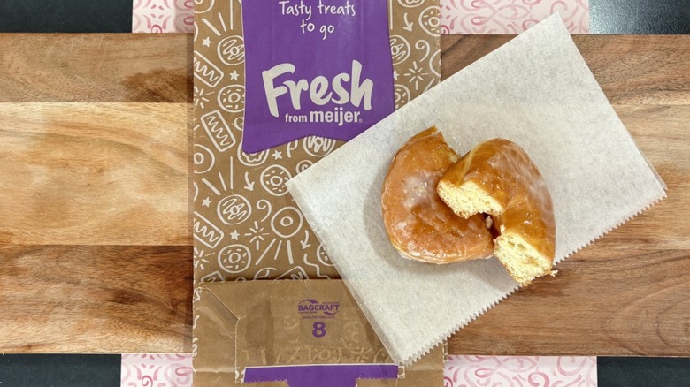 Meijer glazed donut on wax paper on top of donut bag and cutting board