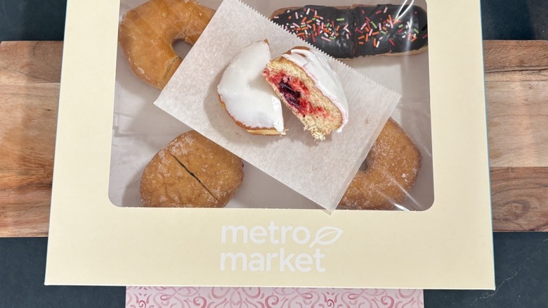 Metro Market iced, jelly-filled donut on wax paper on top of package of assorted