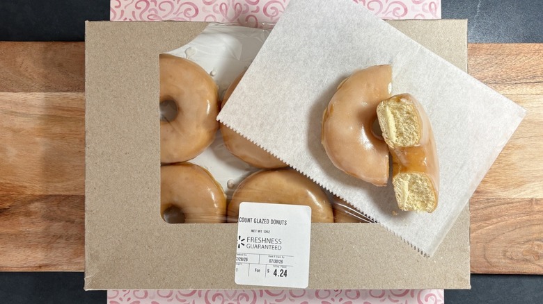 Walmart glazed donut on wax paper on top of packaging, cut in half