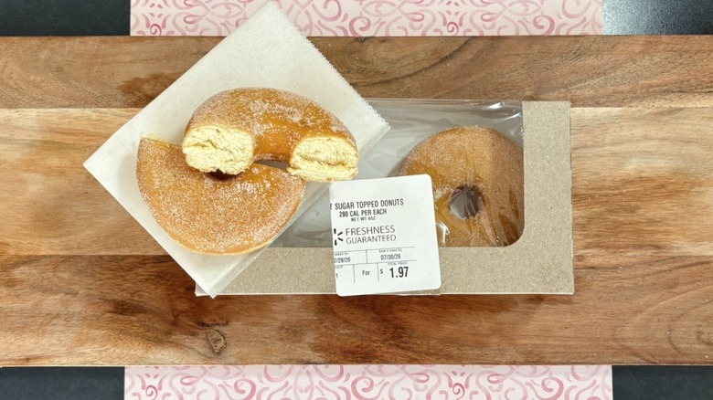 Walmart sugar topped donut on wax paper on top of packaging, cut in half
