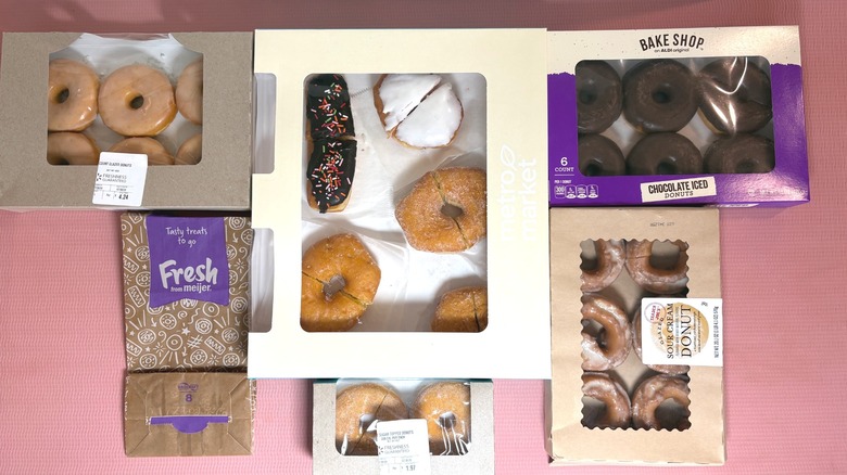 Grocery store donuts in their packaging on a pink background