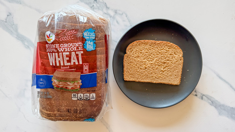 Package of Stop & Shop's whole wheat bread next to a slice of bread on a black plate on a marble countertop