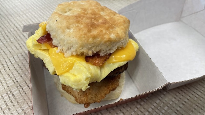 A breakfast sandwich with chicken, sausage, egg, and bacon