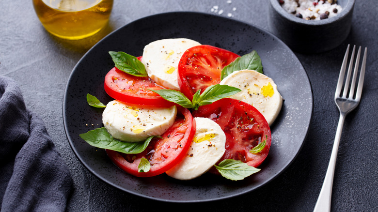A caprese salad on a dark plate