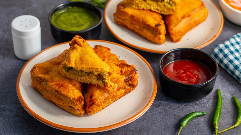 Two plates of bread pakora with condiments