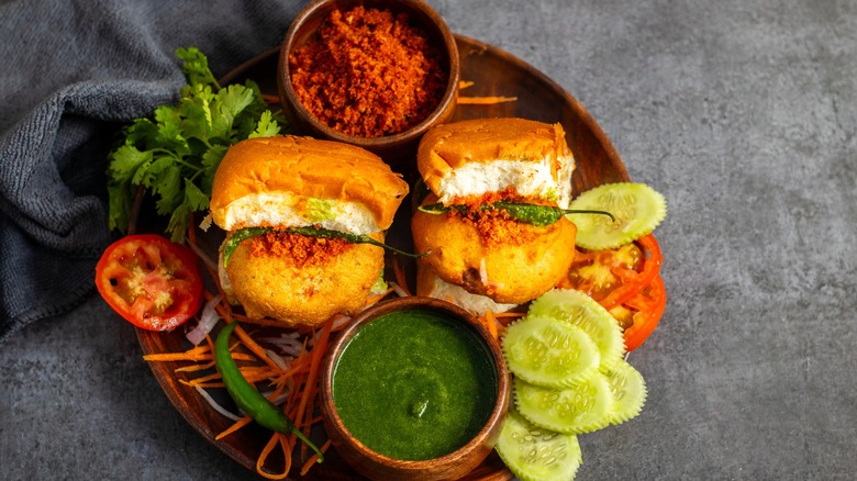 Two vada pav sandwiches on a tray with condiments