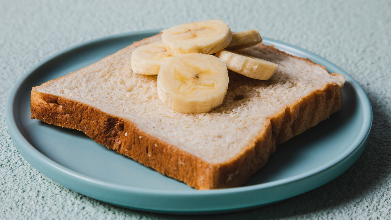 piece of bread on plate with sliced banana on top
