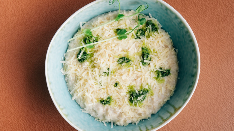 bowl of oatmeal topped with fresh greens and shredded white cheese