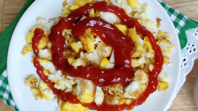 A plate of scrambled eggs covered in a spiral of ketchup