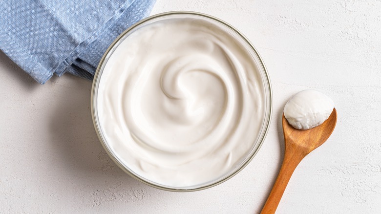 Bowl of sour cream with blue towel and spoon