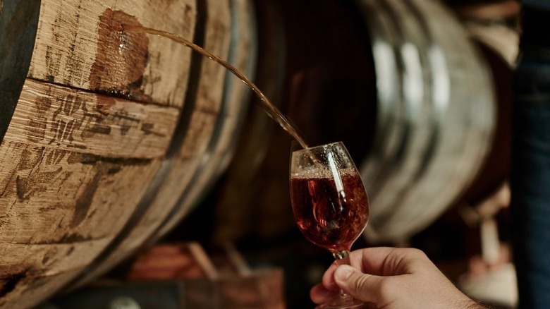 Jack Daniels whiskey pouring out of a wooden barrel into a glass