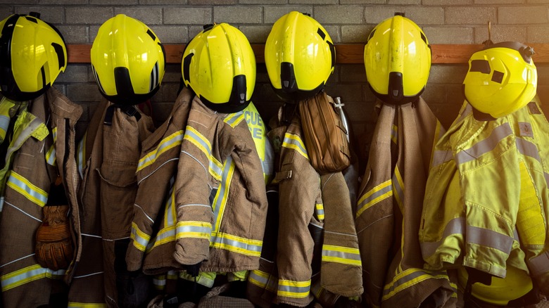 Firefighting jackets and helmets hanging on a wall