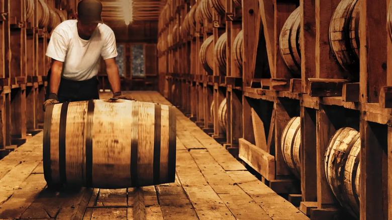 A man rolling a barrel at the Jack Daniels distillery