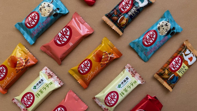 Variety of individually wrapped Kit Kat bars on brown surface