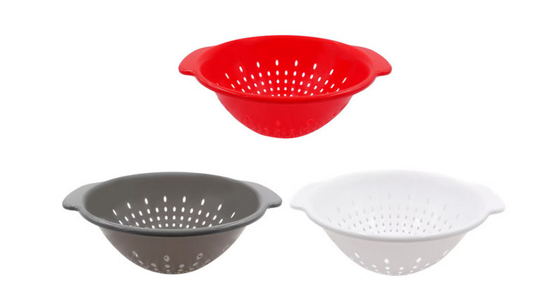 Red, grey, and white colanders against a white background