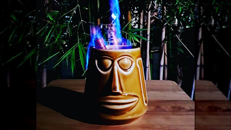 A flaming Kona Coffee Grog cocktail on a bar