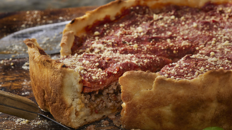 Serving spatula pulling out a slice of Chicago-style deep-dish pizza from the rest of the pie