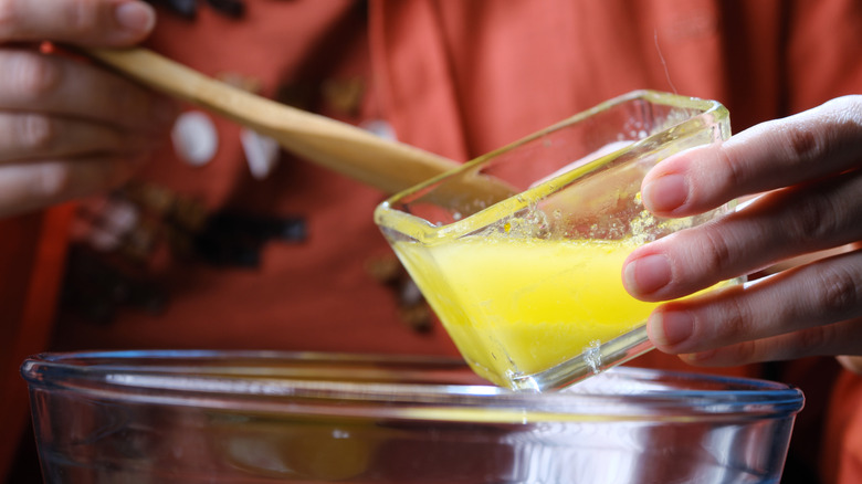 Person adding melted butter to a recipe