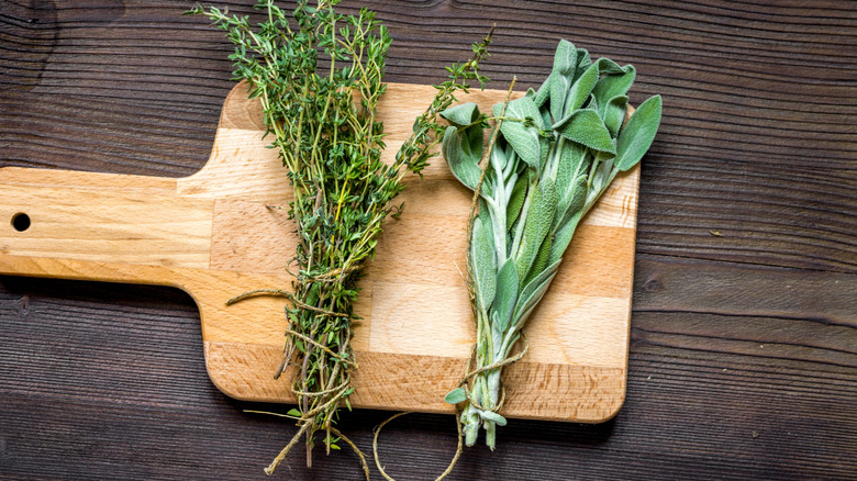 Bundle of sage and thyme on a wooden cutting board