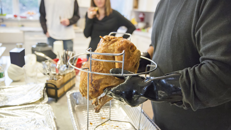 Person handling deep-fried turkey in kitchen