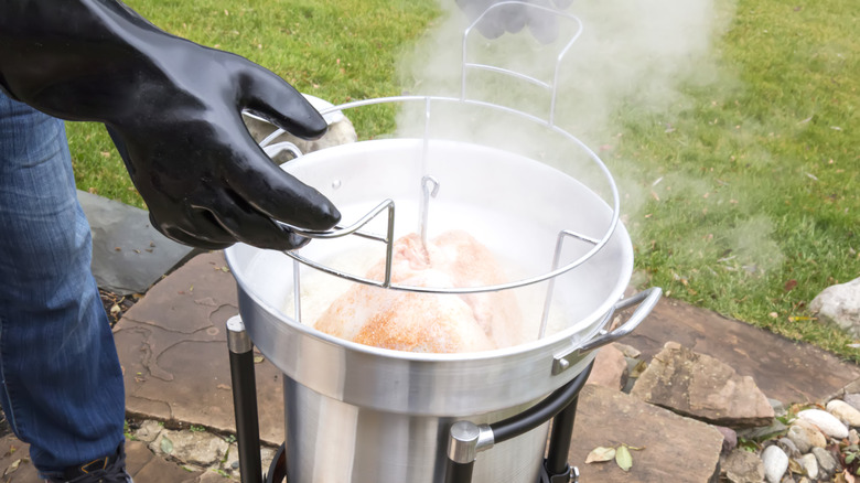 Person frying a turkey wearing gloves