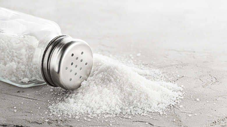 Spilled salt shaker on gray background