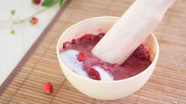 Berries in a cup with sugar and pestle