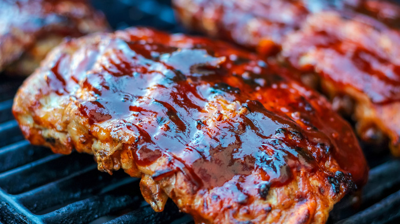 Barbecue sauce on meat on grilling grates