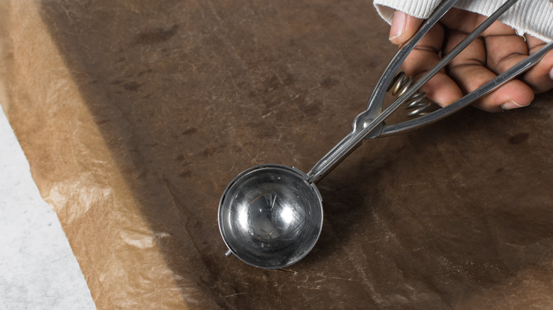 A hand holding a cookie scoop