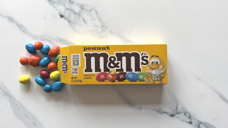 Peanut M&M's spilling from box on marble surface