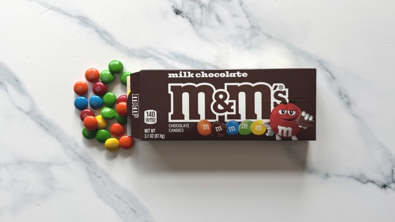 Milk chocolate M&M's spilling from box on a marble surface