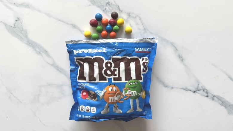 Bag of pretzel M&M's and a few candies on a marble surface