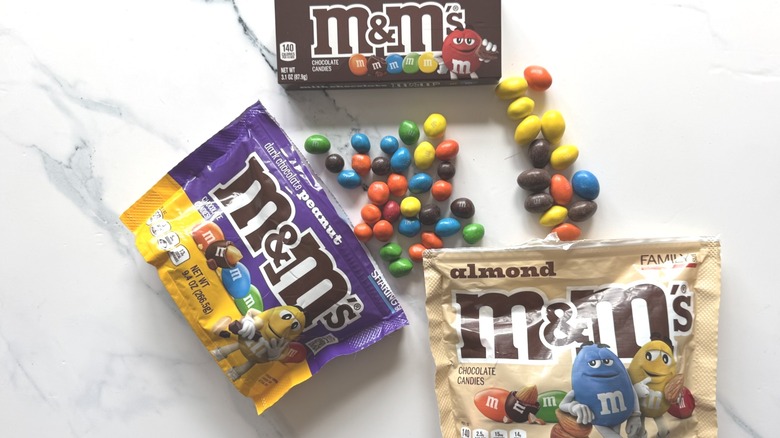 Different flavors of M&M's candy and packaging on marble surface