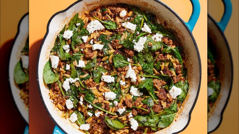 A skillet of ground beef, rice, greens, and cheese