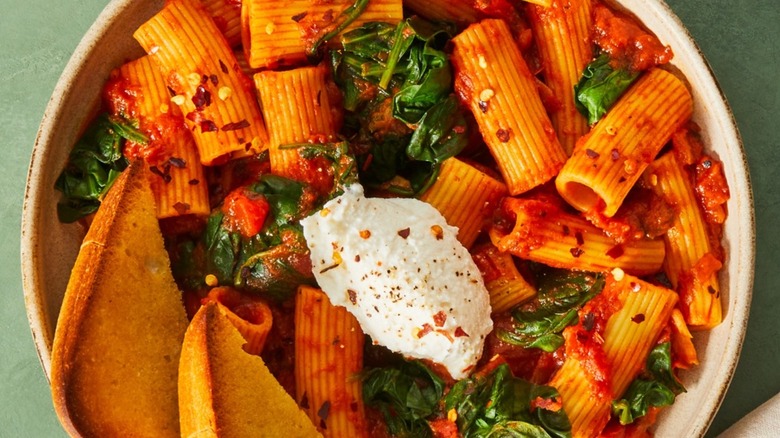 A dish of rigatoni with greens and cheese