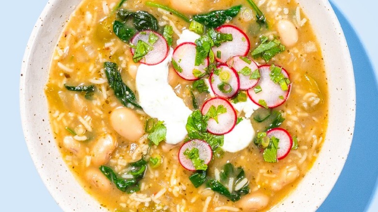 A bowl of chili verde with crema, radishes,
