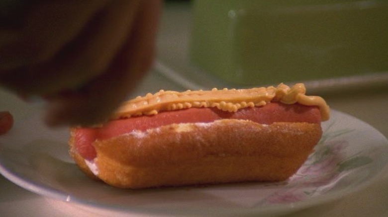 spray cheese being placed on a hotdog