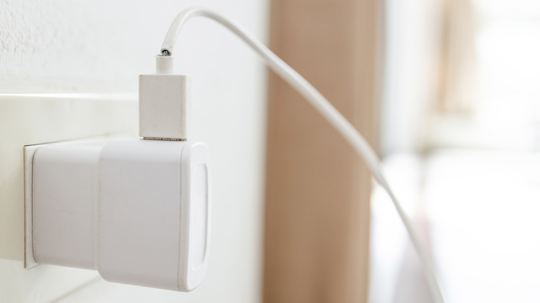 An adapter with a frayed power cord plugged into a wall outlet