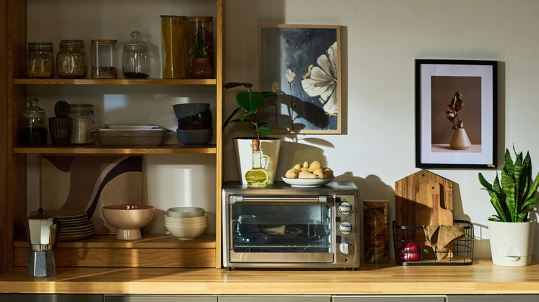 Crowded dinette space with a toaster oven that has several items stored on top of it