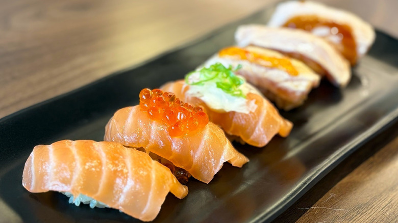 Various pieces of sushi on a black plate