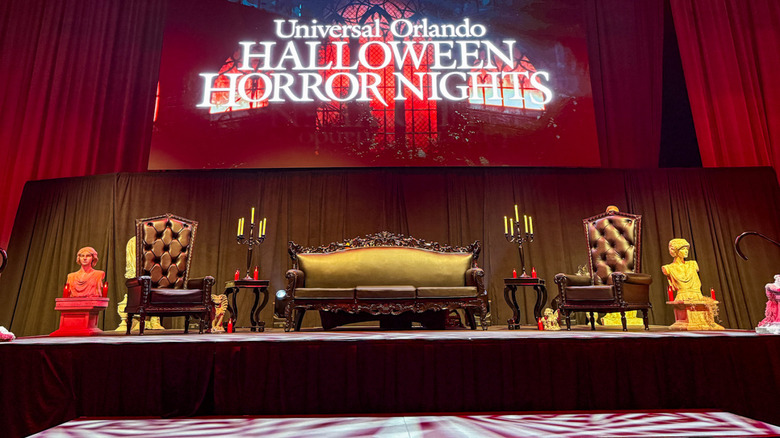 A stage arranged with gothic furniture under a screen that reads "Universal Orlando Halloween Horror Nights"
