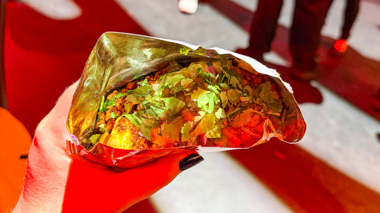 Someone's hand holding a walking taco in a takeout bag