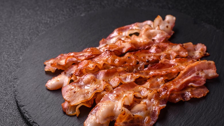 Crispy bacon strips on black background
