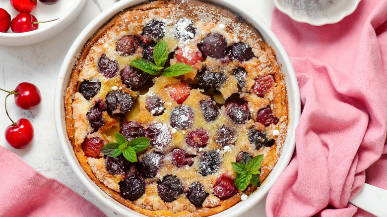 Homemade cherry clafoutis garnished with fresh mint and powdered sugar