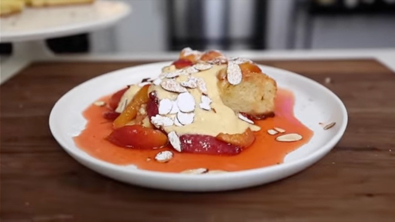 Brioche Tart with Crème Fraîche Custard on a round white plate garnished with poached fruit and shaved almonds