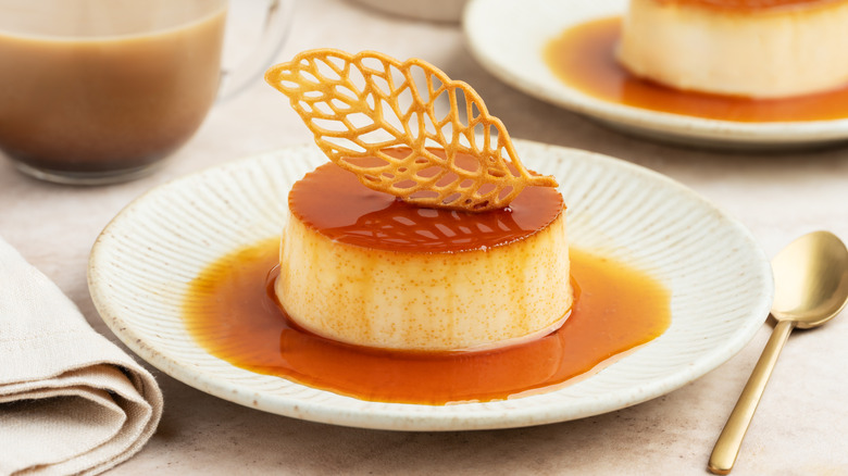 White plate of crème caramel garnished with a leaf-shaped tuile