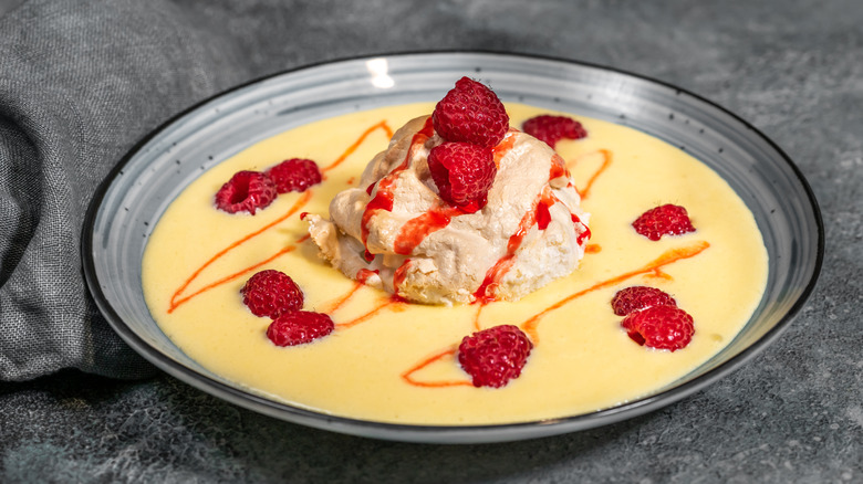 Floating island dessert served in a grey bowl garnished with fresh raspberries