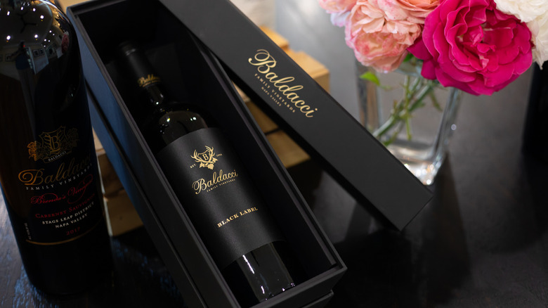 Bottle of Baldacci Black Label in box next to flowers